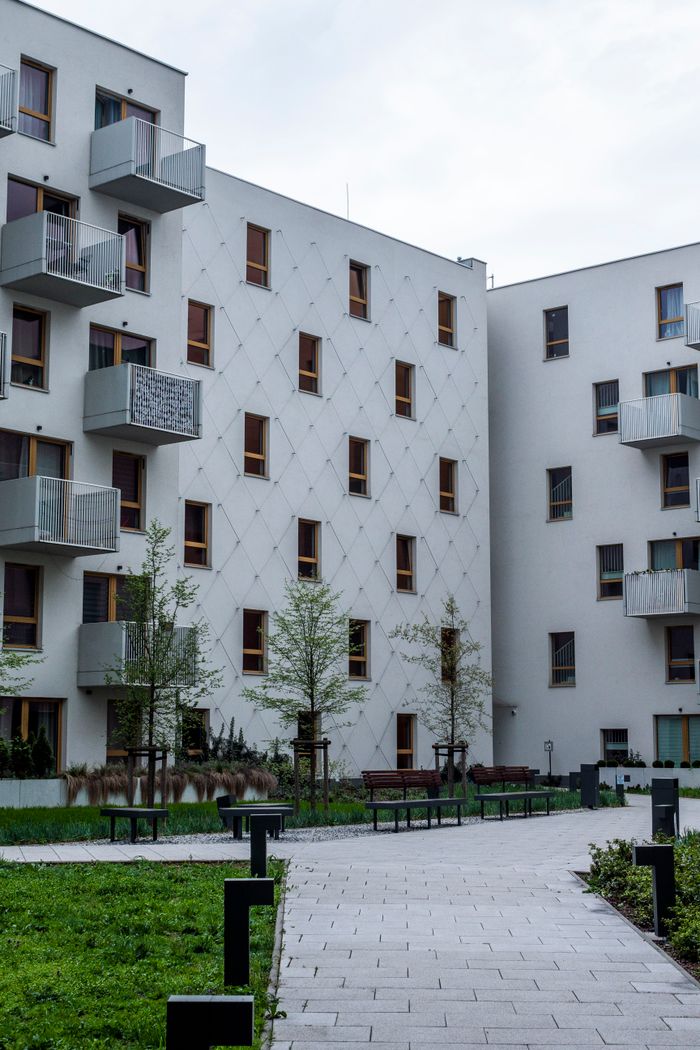 Contemporary white urban apartment buildings with balconies and greenery.